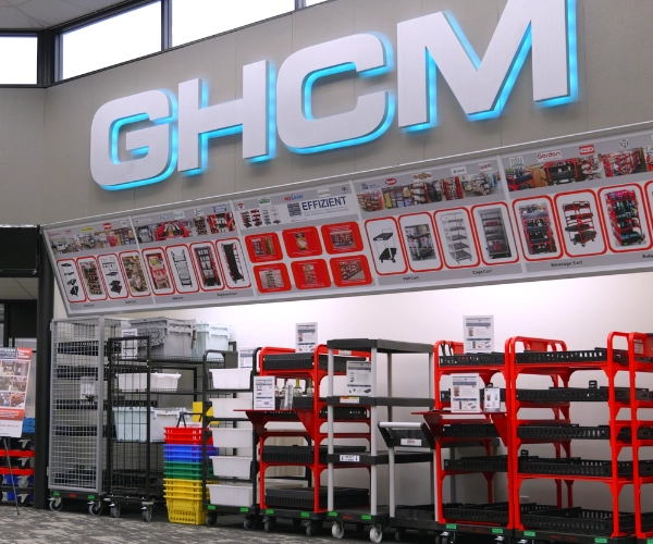 GHCM showroom displaying Effizient carts and molded plastic products under an illuminated GHCM sign