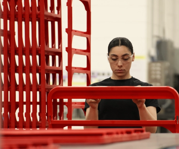GHCM team member inspecting a red molded plastic part