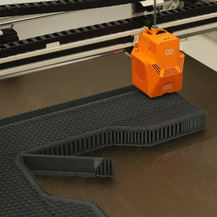 Orange large-format 3D printer head printing a black part