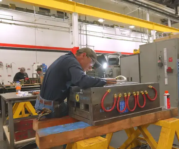Toolroom technician working on an injection mold with red water lines