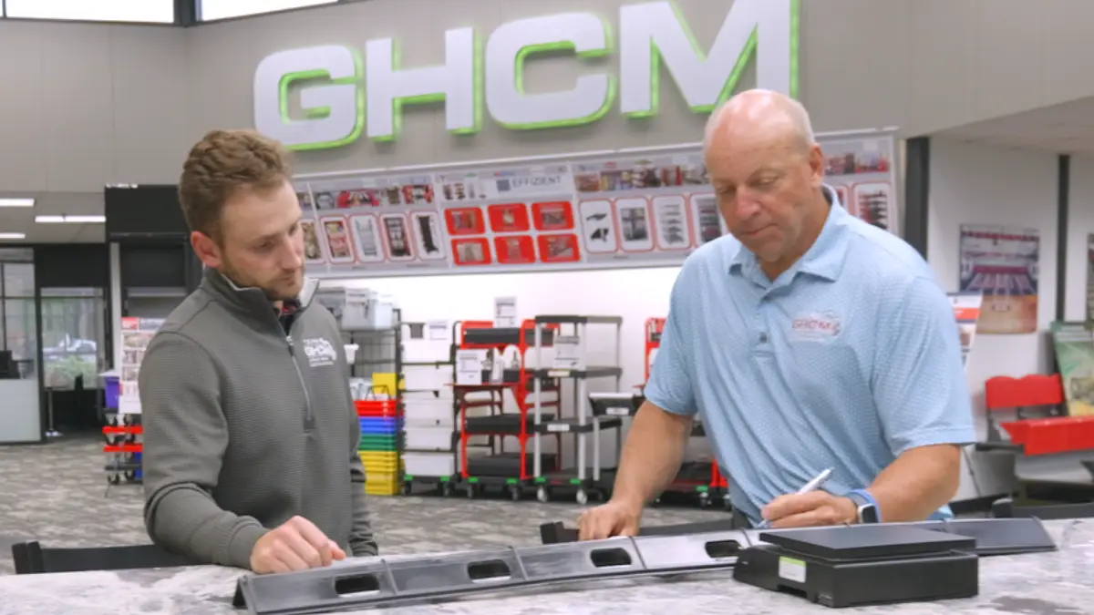 Two GHCM engineers reviewing a molded plastic part at a workbench