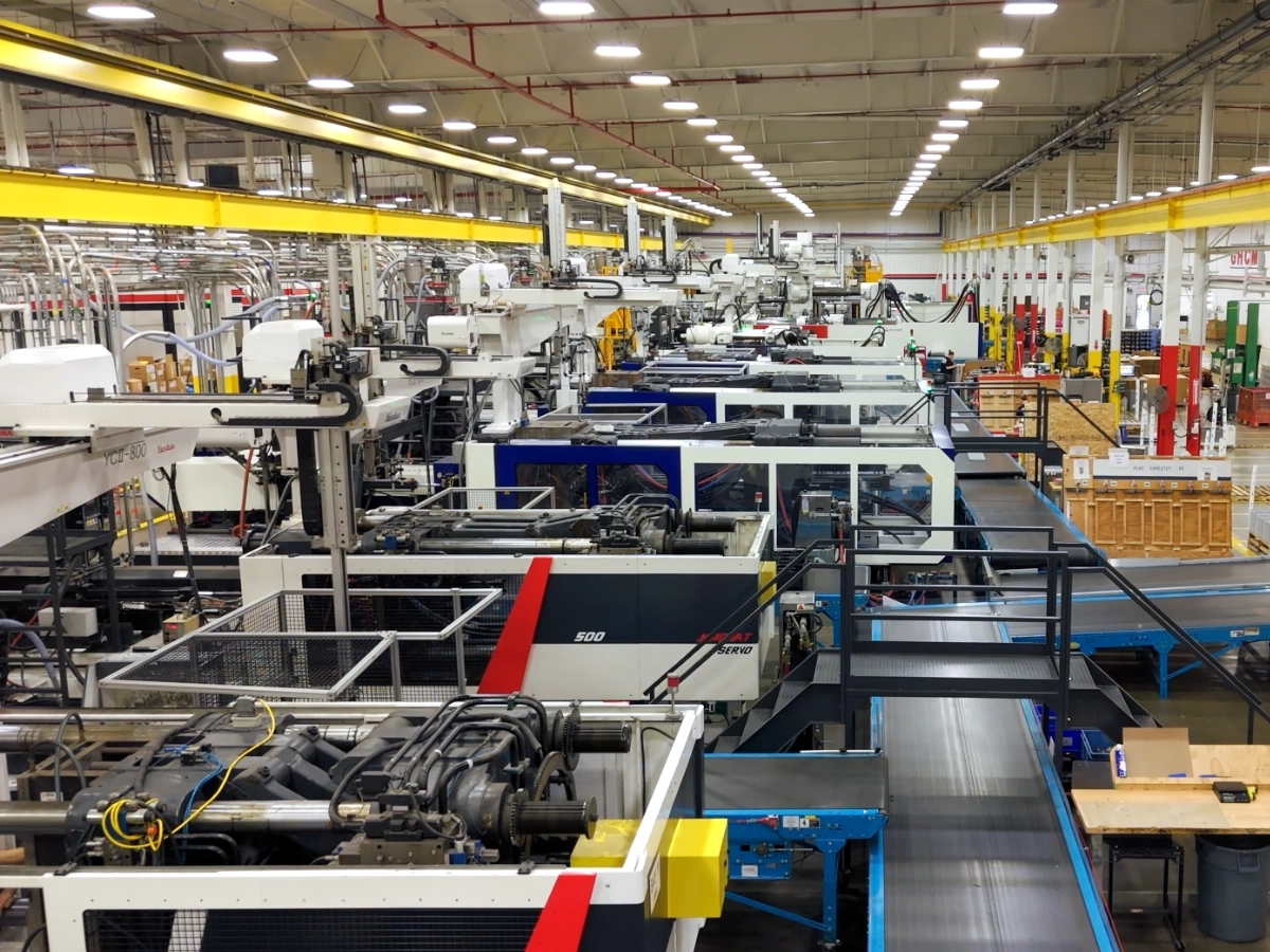 Rows of injection molding machines and conveyors inside the GHCM manufacturing plant